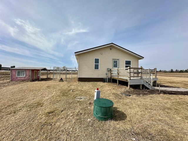 back of property with an outdoor structure, a deck, and fence