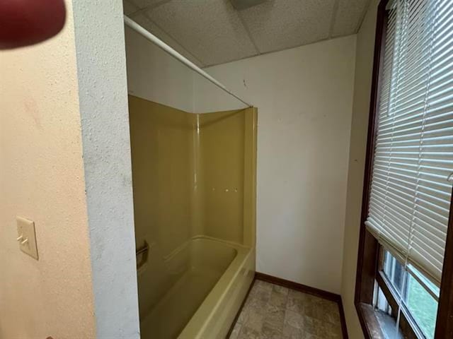 full bathroom with a drop ceiling, baseboards, and  shower combination