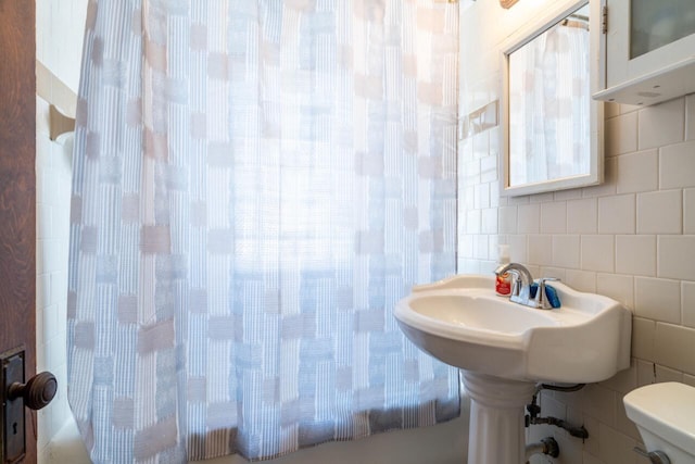 bathroom featuring decorative backsplash, tile walls, and toilet