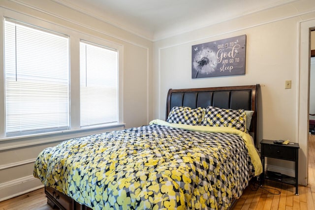 bedroom featuring wood finished floors and crown molding