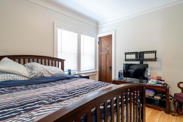 bedroom featuring crown molding and light wood finished floors