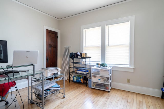 home office featuring a wealth of natural light, crown molding, baseboards, and hardwood / wood-style floors