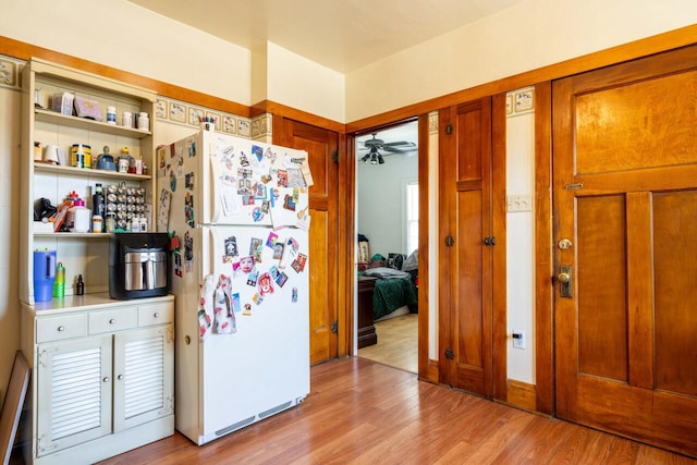 kitchen featuring brown cabinets, a ceiling fan, open shelves, freestanding refrigerator, and light wood finished floors