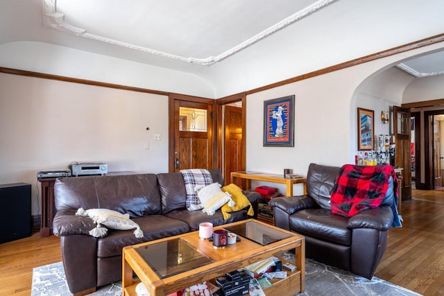 living area featuring arched walkways, vaulted ceiling, and wood finished floors