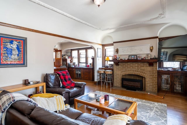 living area with arched walkways, a fireplace, beverage cooler, and wood finished floors