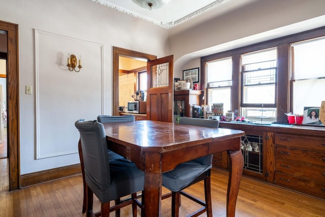 bar with hardwood / wood-style floors, stainless steel microwave, arched walkways, and baseboards