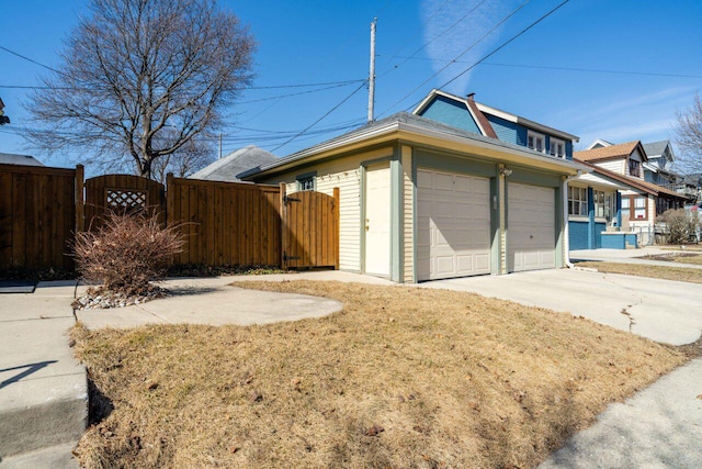 garage with concrete driveway, a gate, and fence