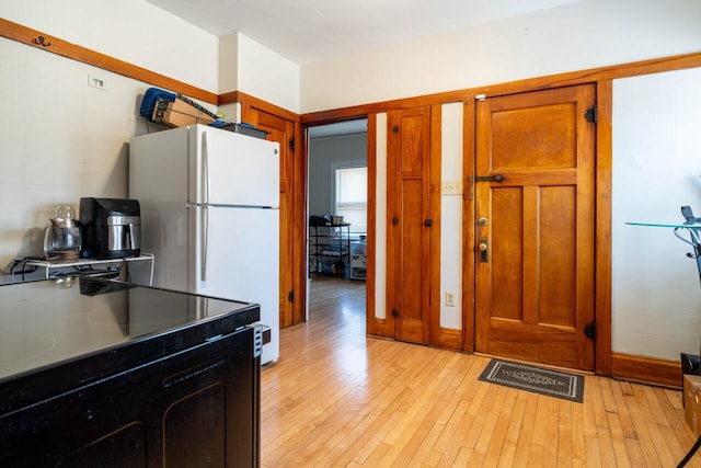 kitchen with black / electric stove, light wood-style floors, and brown cabinetry