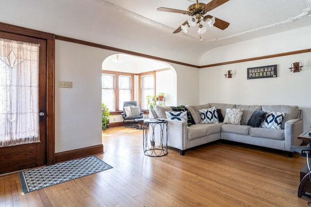 living area with arched walkways, wood-type flooring, baseboards, ceiling fan, and vaulted ceiling