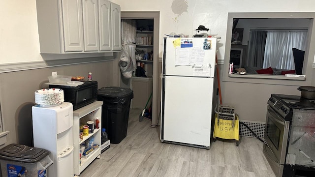 kitchen featuring stainless steel range oven, light wood finished floors, freestanding refrigerator, and black microwave