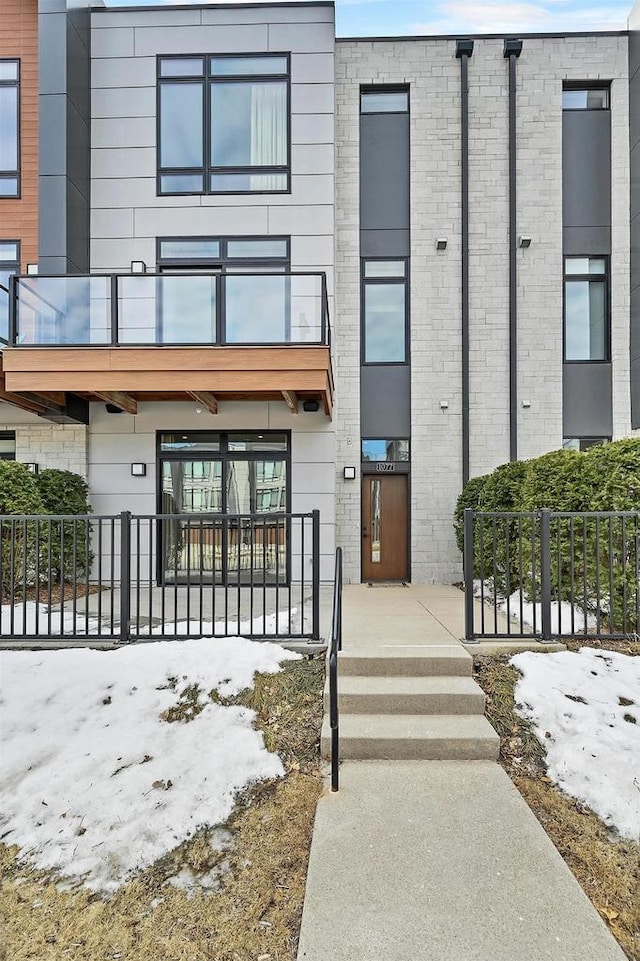 exterior space with a balcony, fence, and brick siding