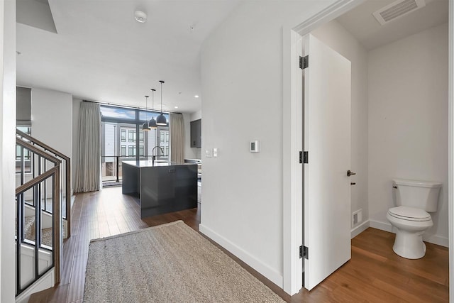 corridor featuring a sink, visible vents, dark wood-style flooring, and stairway