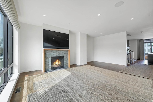 unfurnished living room with visible vents, wood finished floors, recessed lighting, stairway, and a fireplace