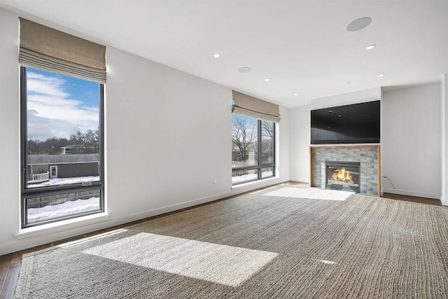 unfurnished living room with recessed lighting, wood finished floors, baseboards, and a tile fireplace