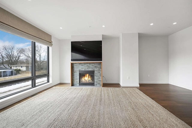 unfurnished living room with a tiled fireplace, recessed lighting, baseboards, and wood finished floors