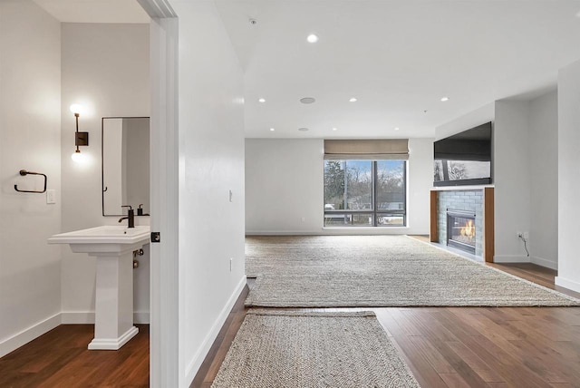 unfurnished living room featuring a glass covered fireplace, wood finished floors, and baseboards