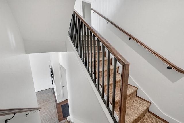 stairs featuring a high ceiling, wood finished floors, and baseboards