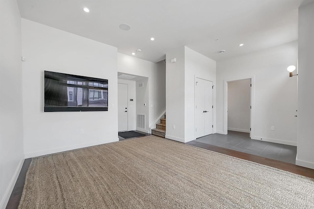 unfurnished living room featuring recessed lighting, baseboards, and stairs