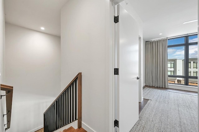 hall featuring recessed lighting, expansive windows, baseboards, and wood finished floors