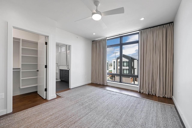 unfurnished bedroom with a spacious closet, recessed lighting, wood finished floors, and baseboards