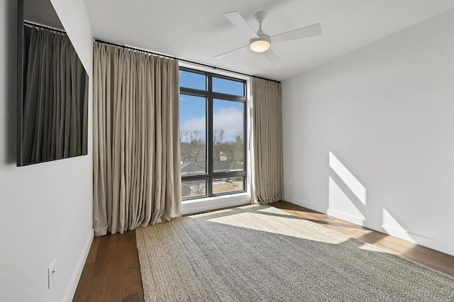 spare room featuring baseboards, a ceiling fan, and wood finished floors