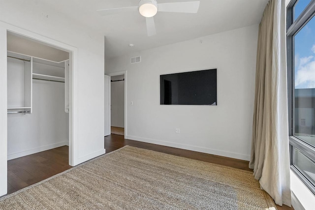 unfurnished bedroom with visible vents, a ceiling fan, baseboards, and wood finished floors