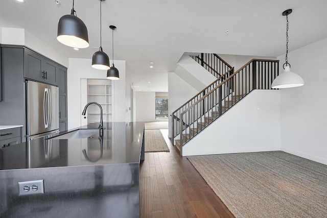 kitchen featuring dark wood-type flooring, gray cabinetry, a sink, open floor plan, and stainless steel fridge