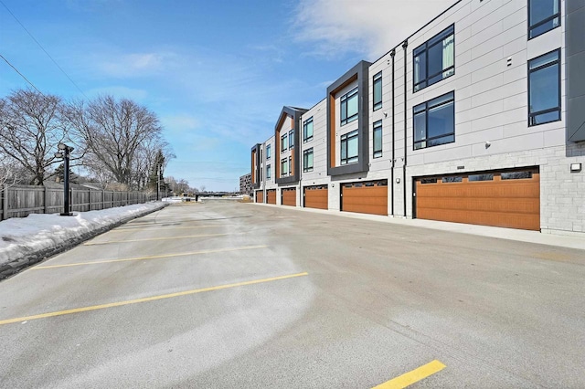 view of parking / parking lot with fence, a garage, and a residential view