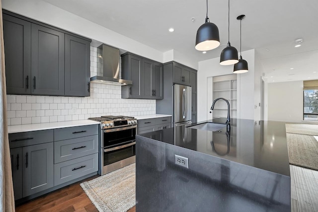 kitchen featuring a sink, wall chimney range hood, gray cabinets, stainless steel appliances, and dark wood-style flooring