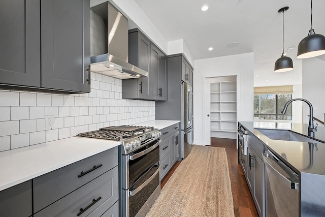 kitchen with dark wood finished floors, a sink, gray cabinetry, stainless steel appliances, and wall chimney exhaust hood