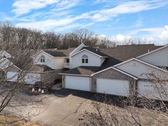 view of front of home featuring a garage, concrete driveway, and a shingled roof