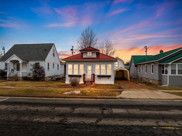 bungalow with metal roof, an outbuilding, concrete driveway, and entry steps