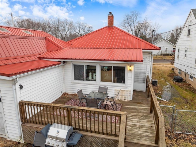 back of house with fence, metal roof, a chimney, and a wooden deck