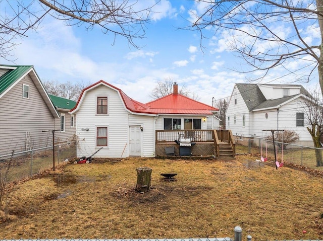 rear view of property featuring a deck, a fenced backyard, a lawn, and metal roof