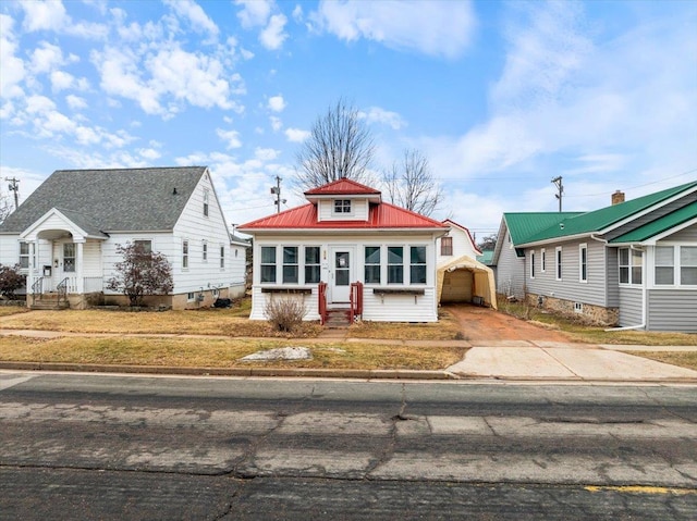 bungalow-style home featuring entry steps, metal roof, and driveway