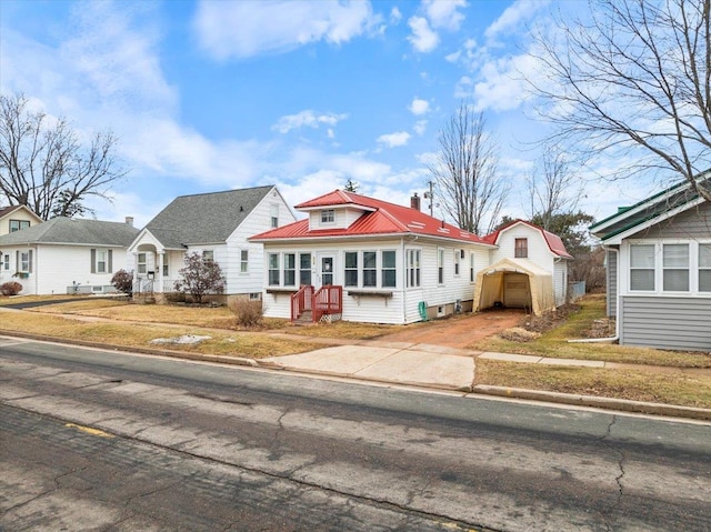 bungalow-style house featuring entry steps, a chimney, driveway, and metal roof