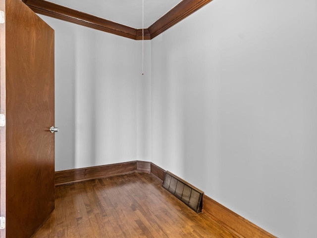 empty room with visible vents, hardwood / wood-style flooring, and ornamental molding