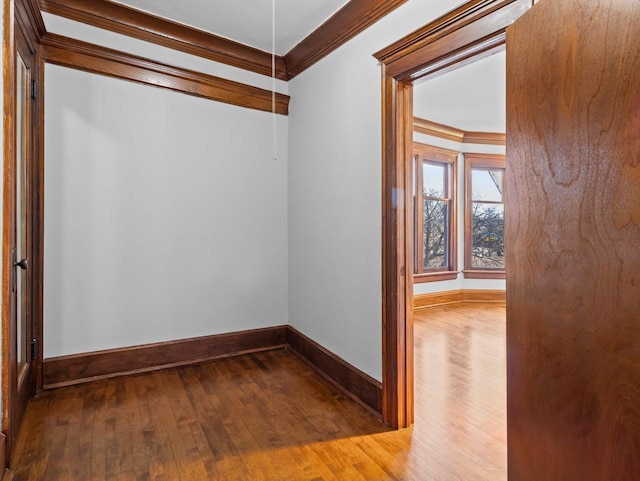 spare room featuring crown molding, baseboards, and hardwood / wood-style flooring