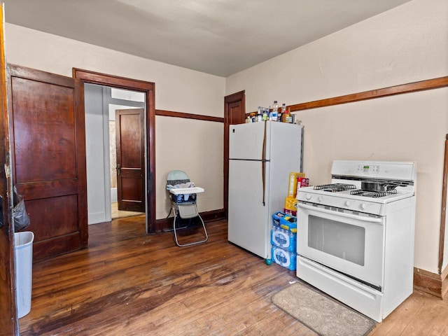 kitchen featuring white appliances, hardwood / wood-style flooring, and baseboards