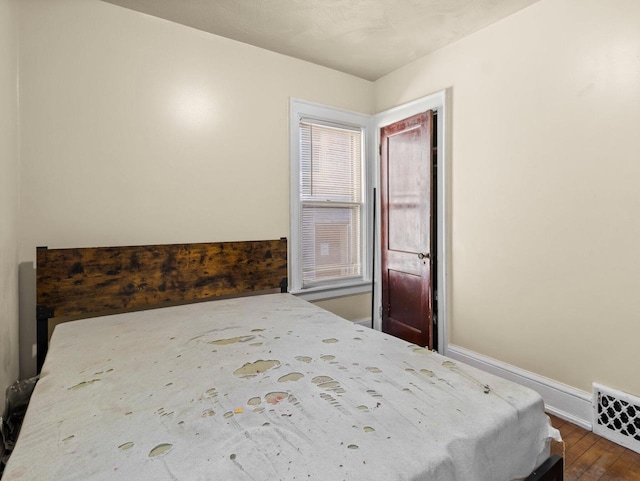 bedroom with visible vents, baseboards, and dark wood-type flooring