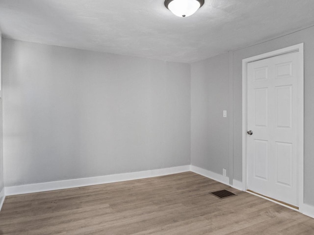 spare room featuring baseboards, visible vents, and light wood finished floors