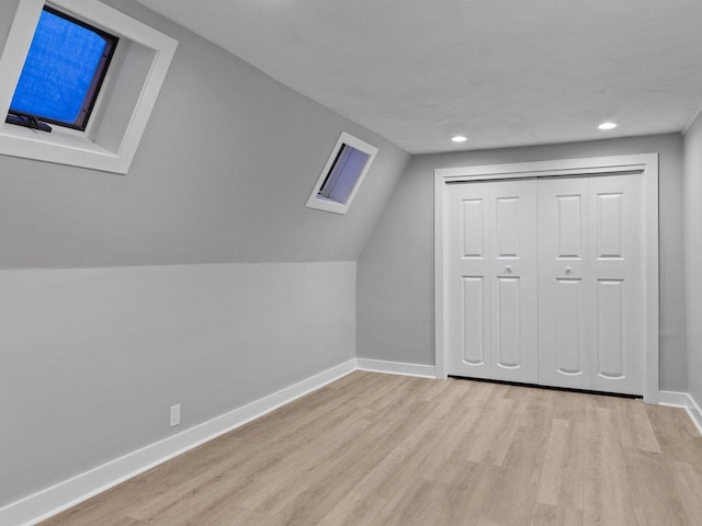 additional living space with lofted ceiling with skylight, recessed lighting, baseboards, and wood finished floors