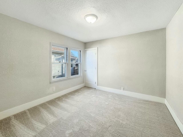 spare room featuring a textured wall, baseboards, carpet floors, and a textured ceiling