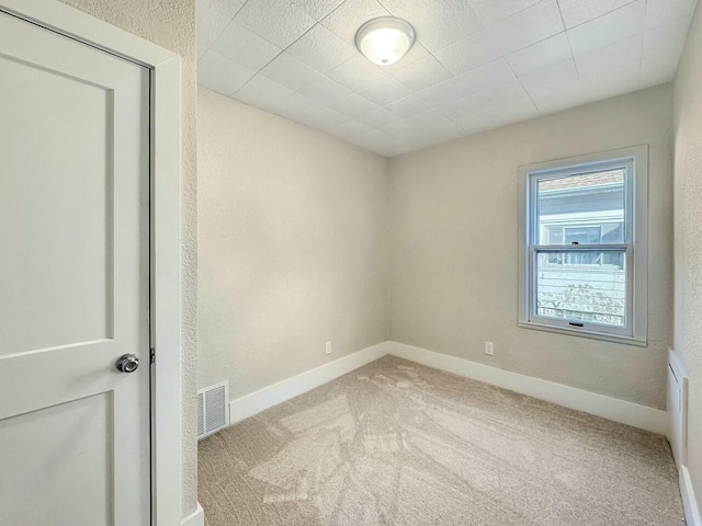 spare room featuring visible vents, baseboards, and carpet floors