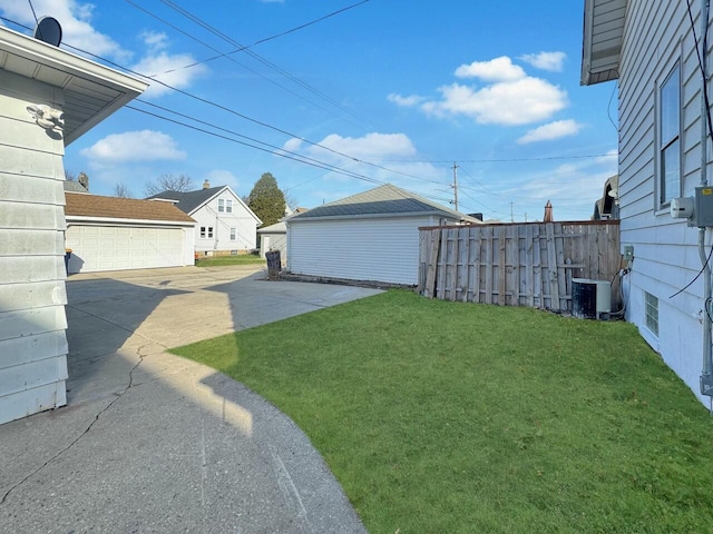 view of yard featuring a detached garage, central air condition unit, fence, and an outbuilding