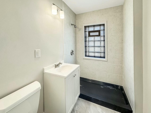 bathroom with vanity, toilet, and a tile shower