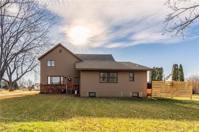 back of house with fence, a lawn, and a shingled roof