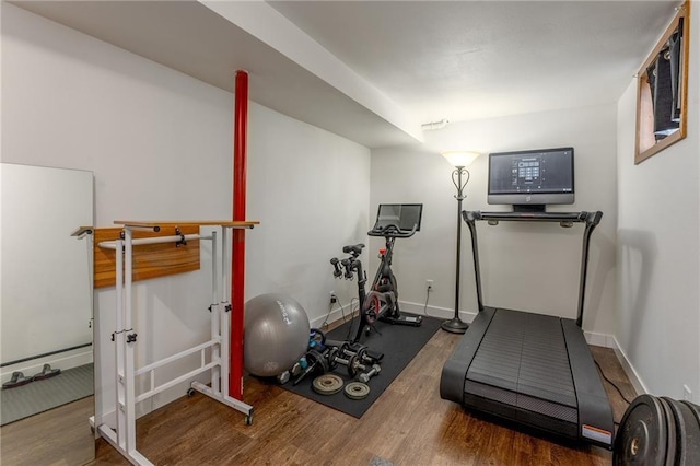 exercise room with baseboards and wood finished floors