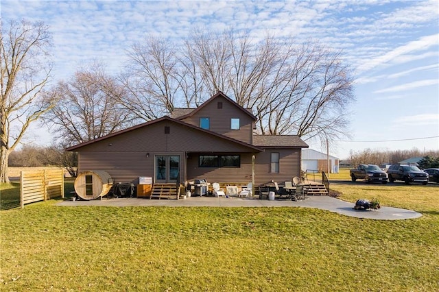 rear view of property featuring fence, entry steps, a lawn, and a patio area