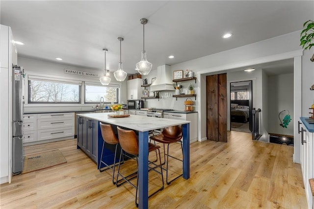 kitchen featuring light wood-style flooring, open shelves, a sink, white cabinetry, and custom exhaust hood